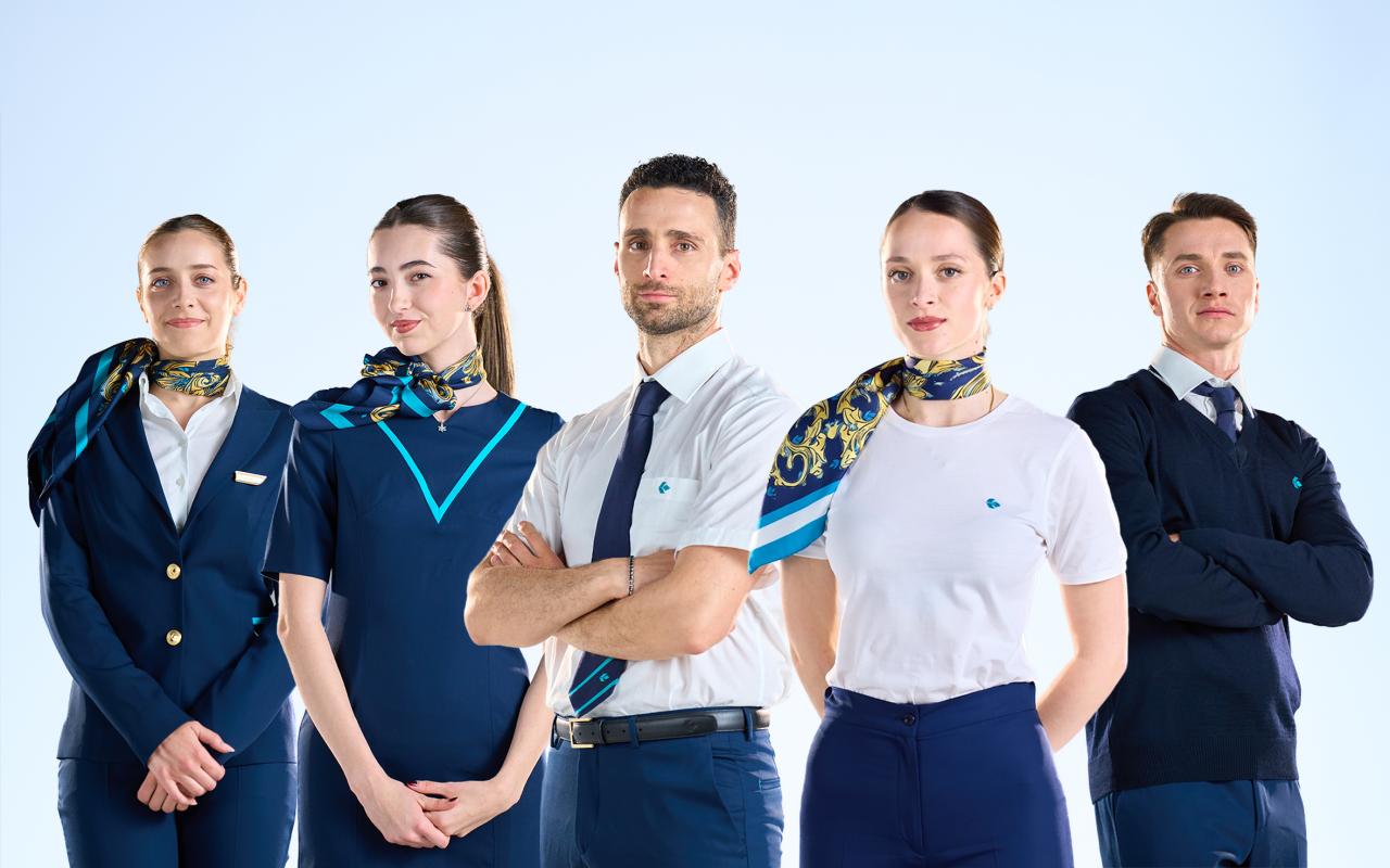 Assistenti di volo Air Dolomiti sorridenti con un aeromobile Air Dolomiti sullo sfondo