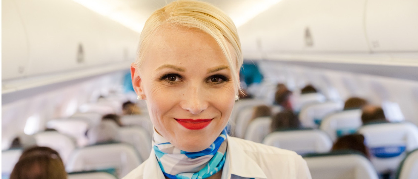 Lächelndes Gesicht einer Air Dolomitis Flugbegleiterin im Vordergrund