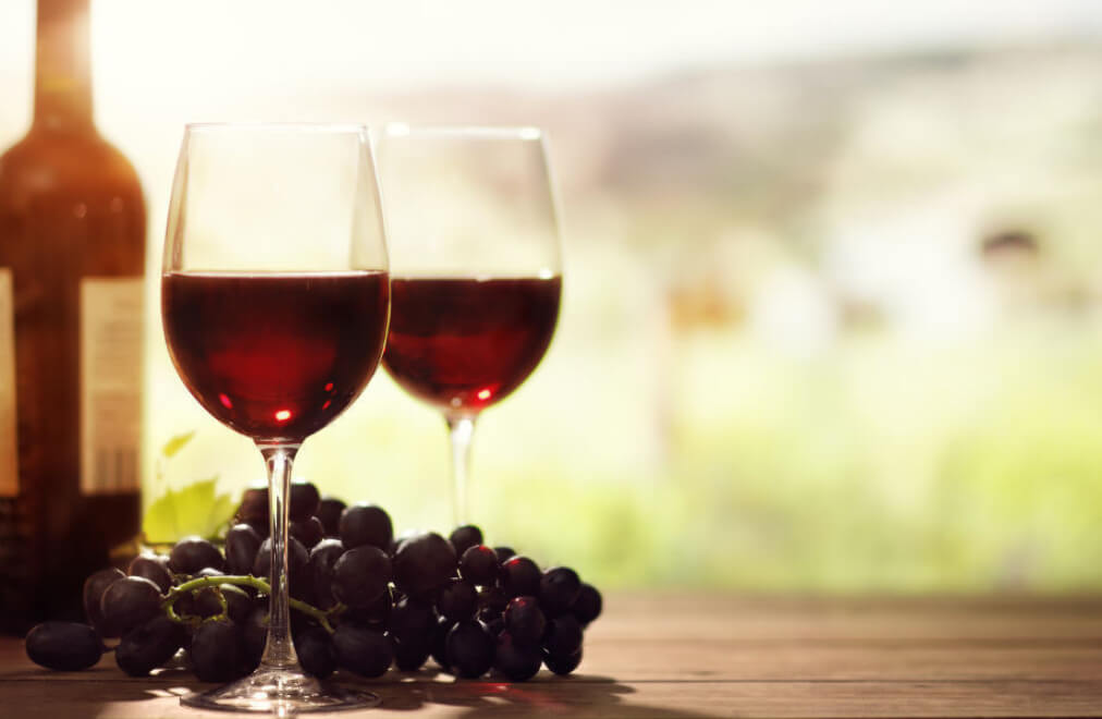 Gläser mit Rotwein, flankiert von roten Weintrauben